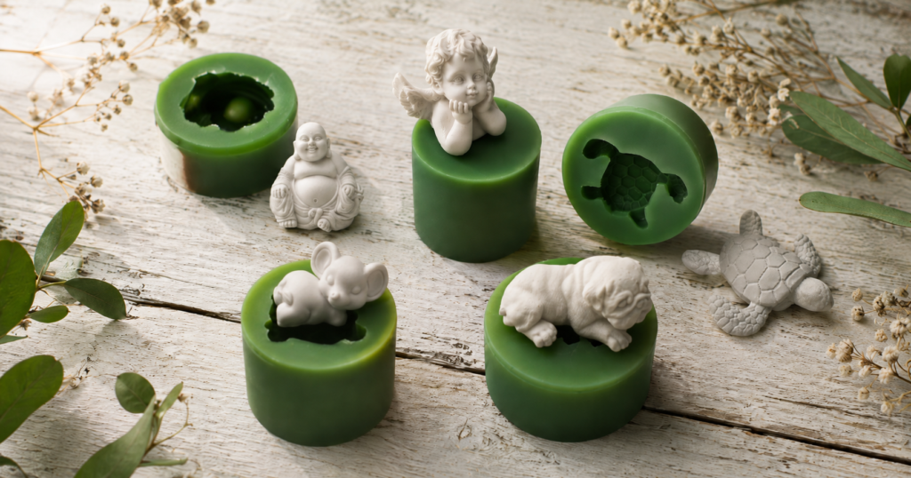 Kleine handgemachte Silikonformen in Grün und Orange mit weißen Abgüssen – Engelchen, Buddha, Schildkröte und Tierfiguren auf Holzuntergrund – Manus Dekoideen